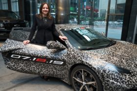 CEO Mary Barra stands with a camouflaged next generation Chevrolet Corvette